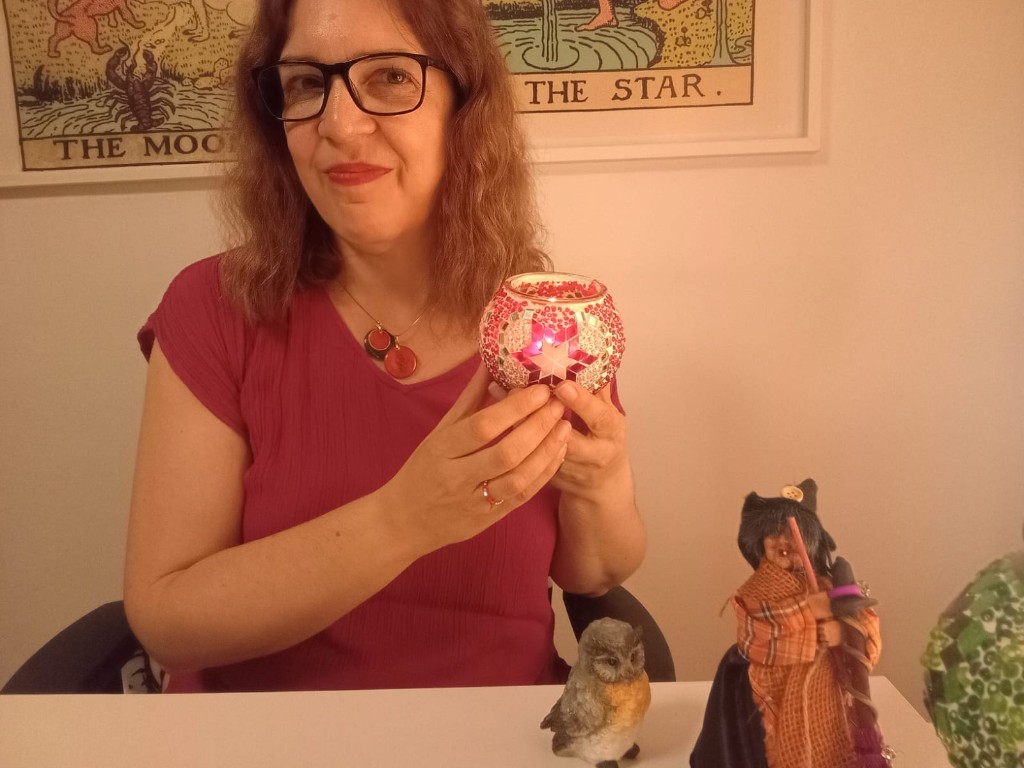 Nuria en su mesa de consulta con portavelas decorativo, búho y figuras de tarot al fondo